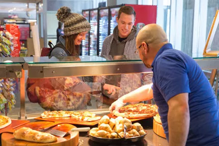 Sodexo employee serves pizza to two students on campus.