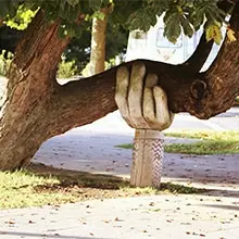 sculpture of hand holding up tree branch tree ground
