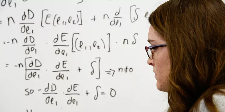 Student working on an equation on a whiteboard.