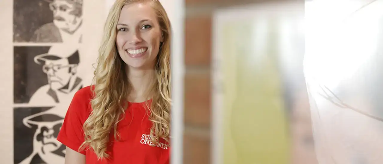 Jessica Kemmerling stands in the Martin-Mullen gallery at SUNY Oneonta, beside a woodcut print she entered in the Annual Juried Student Art Exhibition. Kemmerling, a computer art and communication studies major from Owego, NY, will pursue a master&rsquo;s in art direction at Virginia Commonwealth University following her graduation from SUNY Oneonta on May 16, 2015. The woodcut, titled Parkinson&rsquo;s Disease, depicts her grandfather&rsquo;s decline.