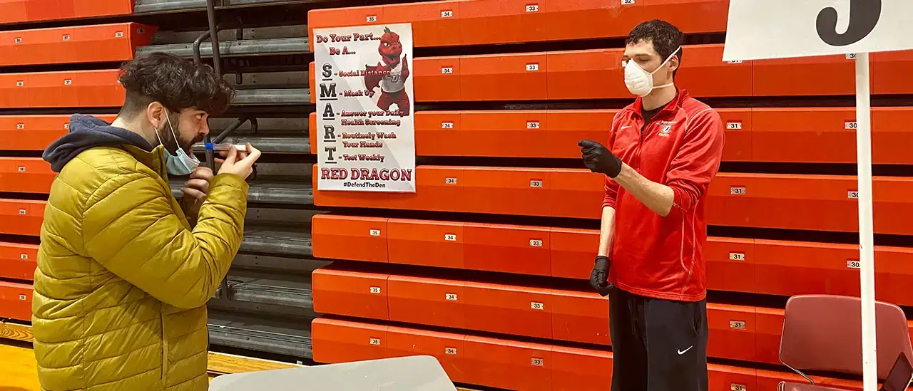 Student doing a COVID-19 saliva test at the Alumni Field House pool testing center