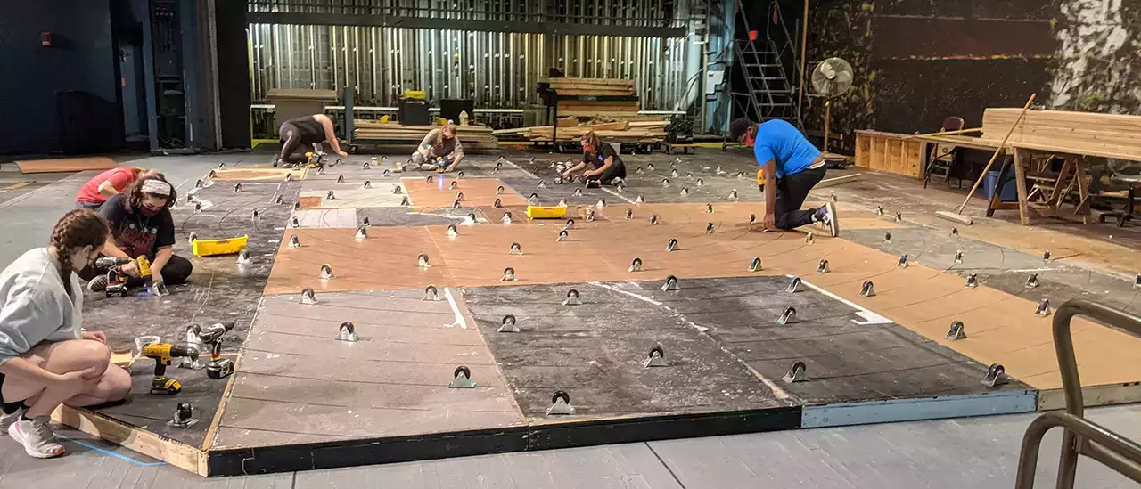 Students fix casters on the bottom of a rotating set