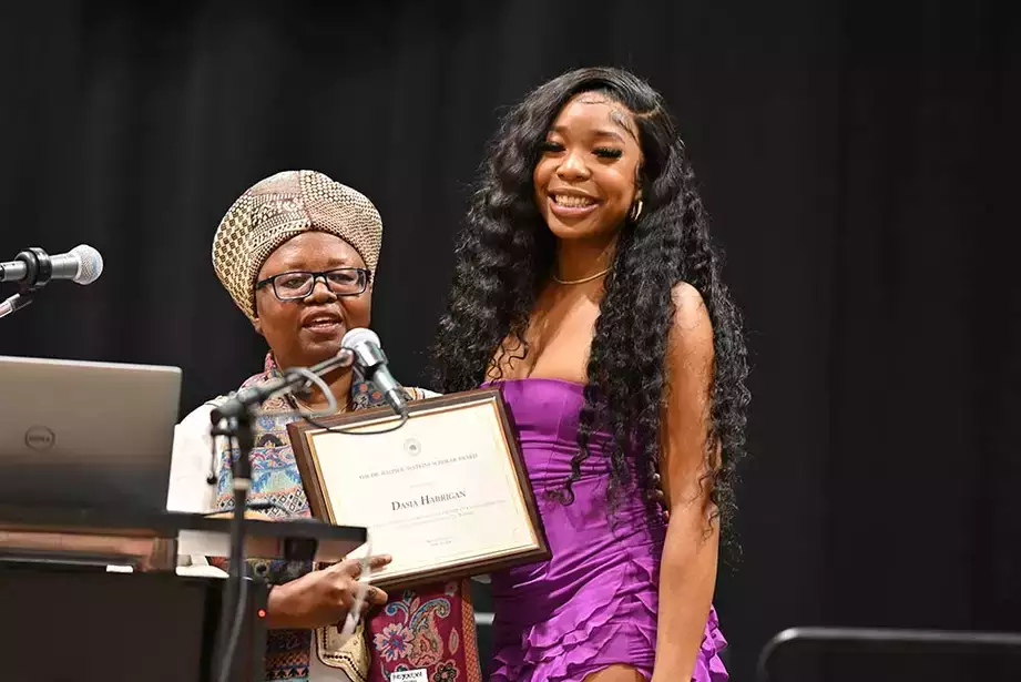 Student poses with award at Kente Graduation