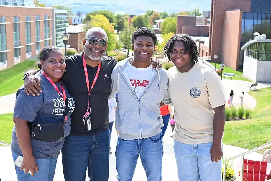 Happy family posing overlooking the SUNY Oneonta campus during Family Weekend