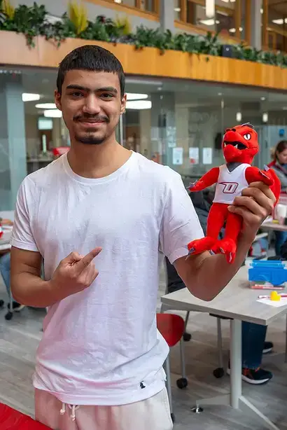 Student poses with a Red the Dragon doll during Spring Fling