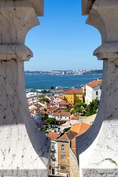 A view from an elevated position of a coastal Portugese town, framed through heavy balustrades. 
