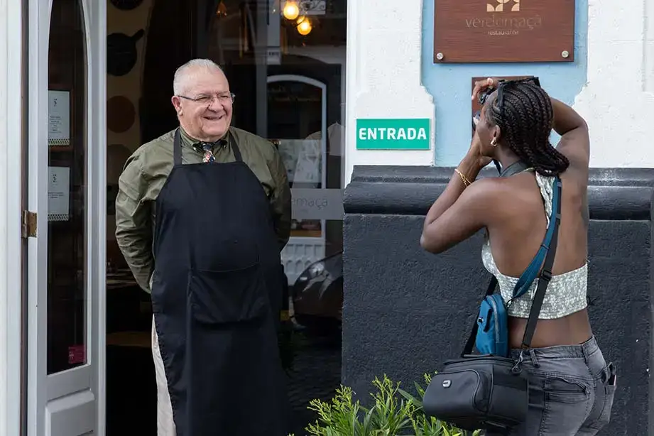 A local shopkeeper poses for a photograph taken by a student.