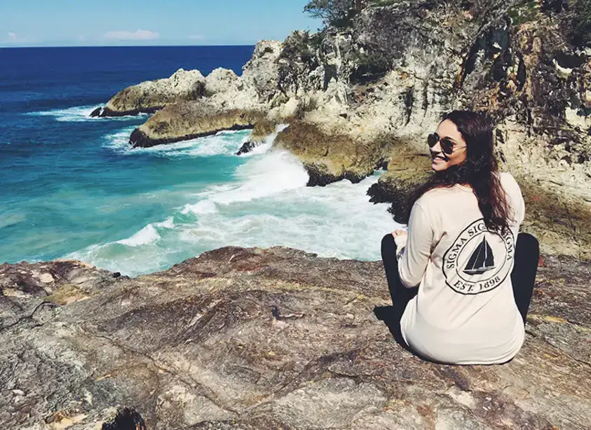 Jordryn Choen sits on a rock outcropping overlooking the ocean in Queensland, Australia.