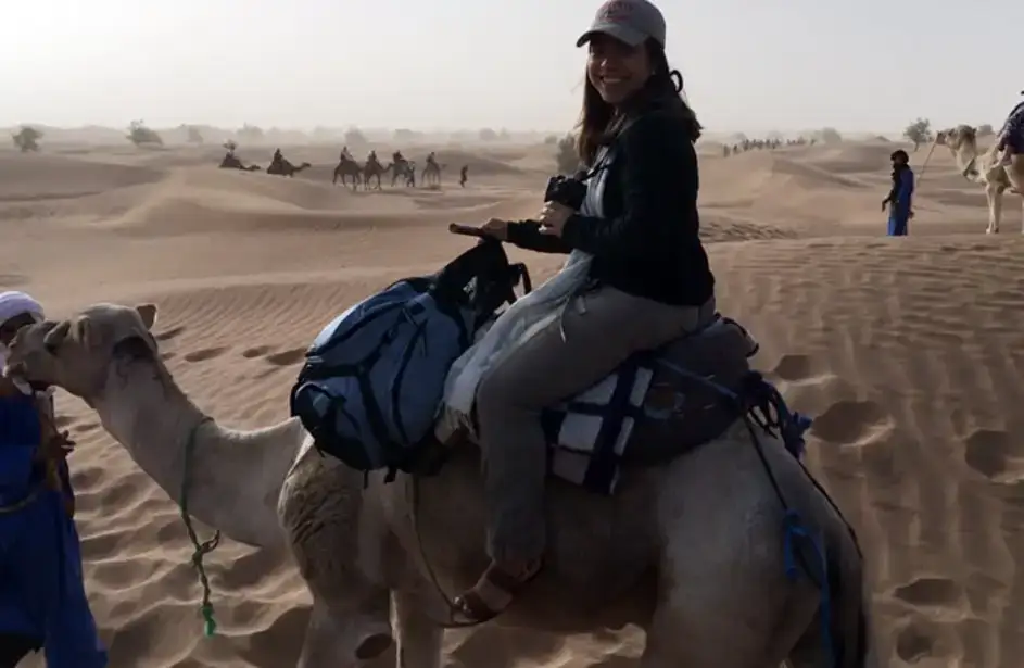 Alessia Cipriano sits atop a camel in the deserts of Morocco.