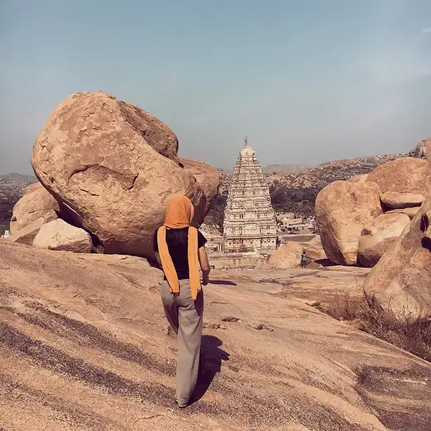Victoria Savoie stands atop large boulders looking out toward the Virupaksha Temple in Hampi, India.