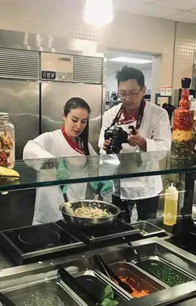 Julia works on donut batter while JP takes photos.