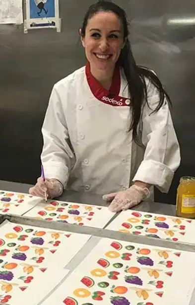 Julia Goolia poses with her Wonka paper in the kitchen at Wilsbach Dining Hall.