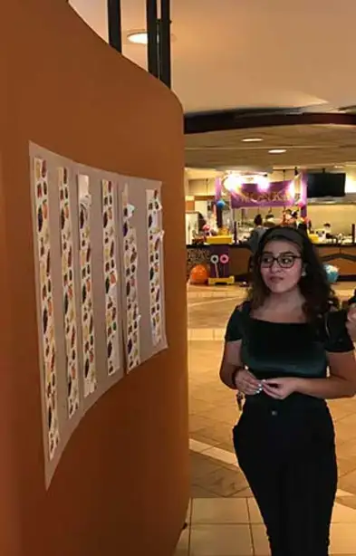 Student poses next to the multi-colored Wonka paper in Wilsbach Dining Hall.