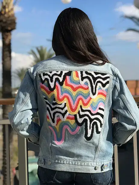 Model wears a denim jacket with colorful lines on the back.