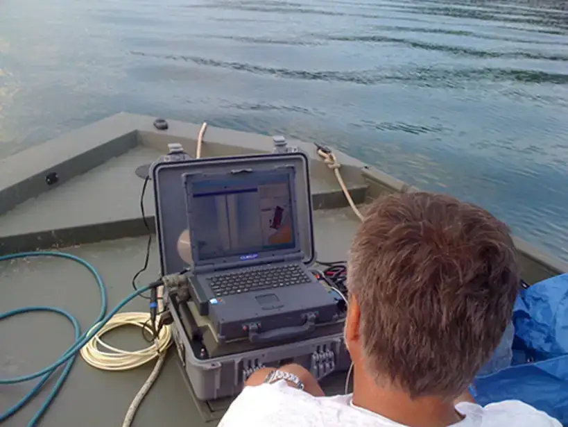 BFS Dive team member looks over a laptop on the boat deck.