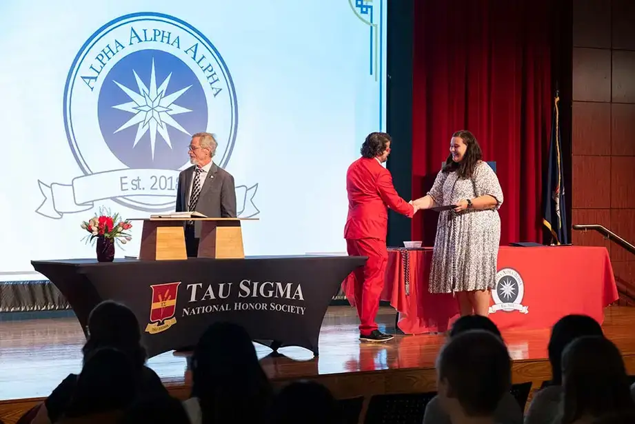 Tri-Alpha eboard President Brianna Trent presents staff inductee, Thomas Ragland with his cords.