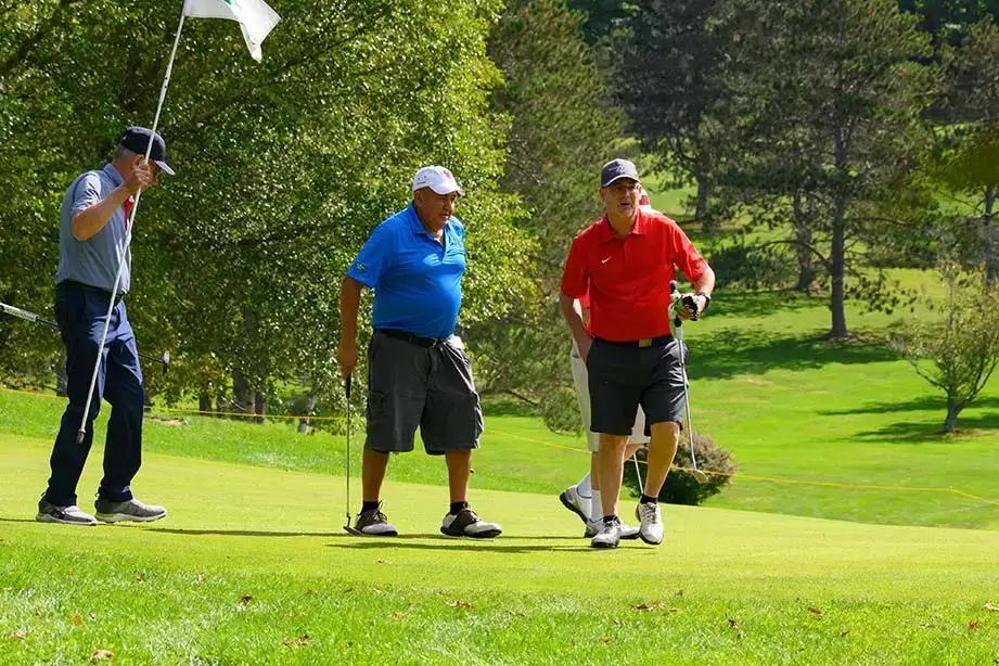 Contestants at the Red Dragon Open stand to the side of a green.