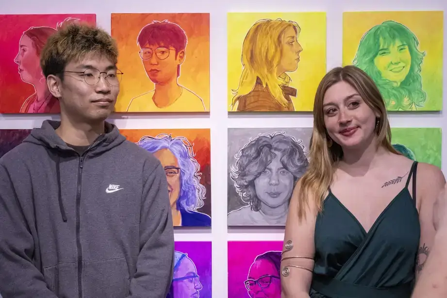 Artists posing for a photo in front of their colorful fine art exhibit during a Juried Student Show