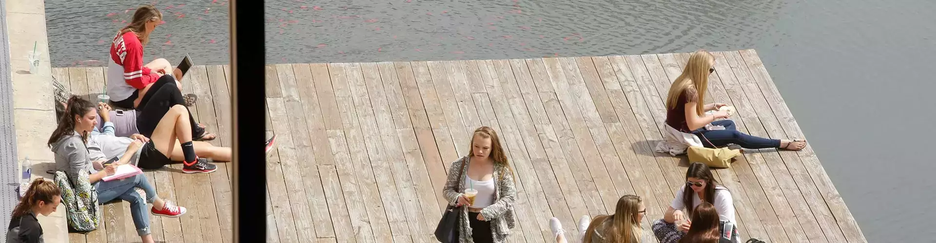 Students studying on the dock at the Hunt Union pond