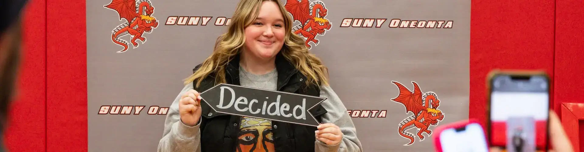 An admitted student posing for a photo with a "Decided" sign