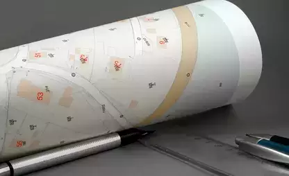 Rolled up map on a desk with a ruler and pens/pencils