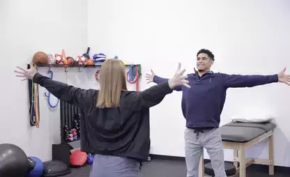 Physical Therapy intern and practitioner facing each other with their hands spread out