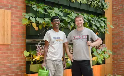 A.J. Read Science Discovery Center interns standing near an indoor garden holding a watering can and shovel