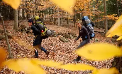 Two people carrying backpacks hiking at College Camp