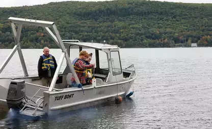 Three people on a boat collecting data from Otsego Lake