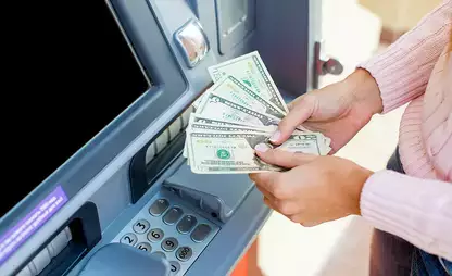 Person counting cash in front of an ATM