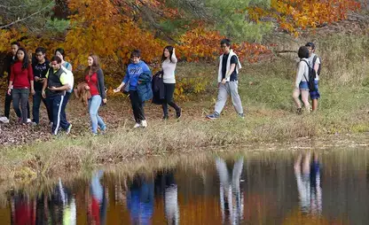 Students walk near a pond during fall