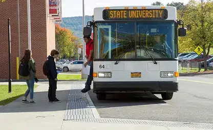 Students board a bus at the stop outside Fine Arts