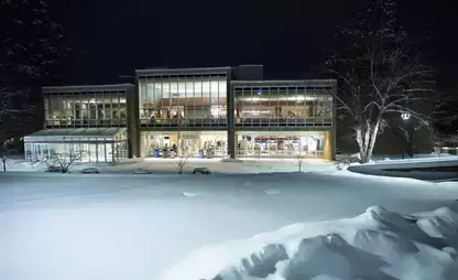 Mills Dining Hall seen on a snowy night from across a snow-covered field
