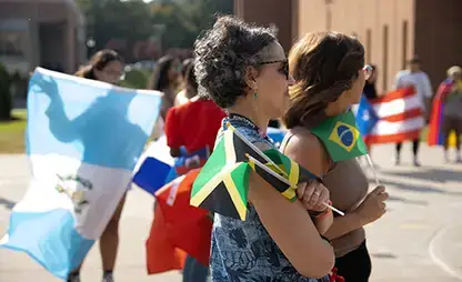 Supporters standing in the quad holding a variety of flags during a Hispanic Heritage Month event