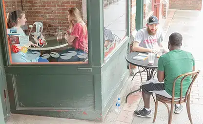 Patrons sitting at tables inside and outside at a coffee shop in downtown Oneonta