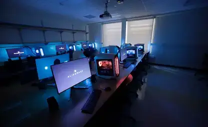 Alienware computer stations glow blue and purple in a darkened lab room.