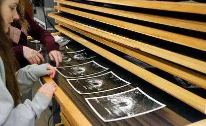 Students review black and white prints in the dark room common room.
