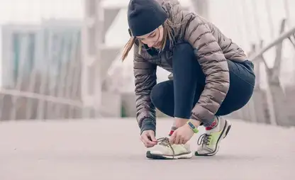 Jogger dressed for cold weather stops to tie their shoes.