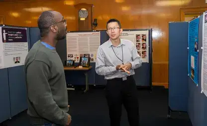Two people discussing their research at a Life of the Mind Faculty Showcase