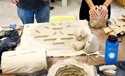 A student works a lump of clay during a sculpture class.