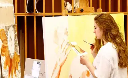 Student works on a large format painting in an art department studio.
