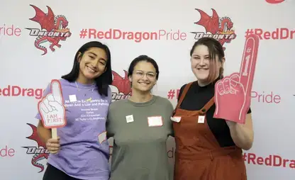 3 students posing for a photo at First-Generation Celebration Day, holding "#1" and a "I AM F1RST" signs