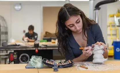 Student works on a sculpted 3D model in studio.