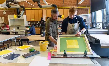 Student works with a large screen during screen printing class.