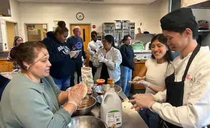 Members of the ADI&Oacute;S student club gather around a kitchen island taking part in a cooking class.