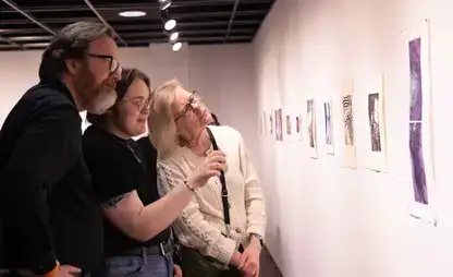 A student describes art spanning a wall to their family members during a Project Open Call exhibition