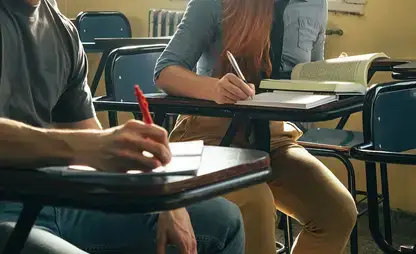 Students seated in a classroom take notes.