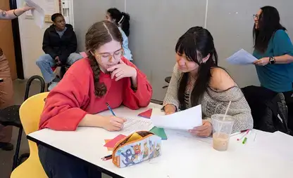 Students sit at a table looking over a document together.