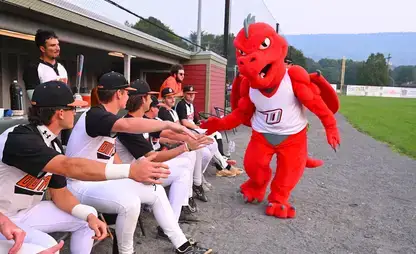 SUNY Oneonta mascot Red gives high fives to members of the Oneonta Outlaws baseball team.