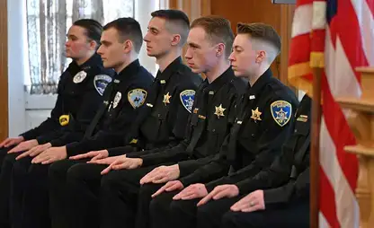 Recent officer graduates of the police academy await their diplomas.